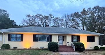 Dinnwiddie apartment for rent - A house with a grey roof and white walls is surrounded by greenery.
