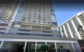 Honolulu apartment for rent - A tall white building with balconies and a sign that reads "Bank of Lisbon".