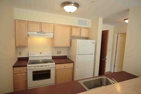 Exeter apartment for rent - A kitchen with a white refrigerator, white stove, and wooden cabinets.