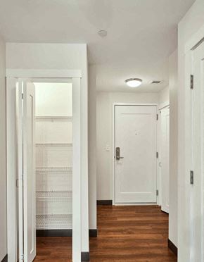 Portland apartment for rent - A white door is open to a hallway with wood floors.