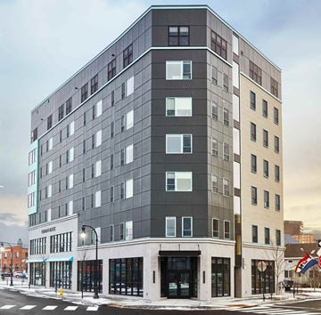 Portland apartment for rent - A modern multi-story building with a glass facade is the main focus of the image.