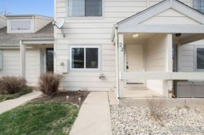 Fort Collins apartment for rent - A white house with a grey garage door and a small garden in front.