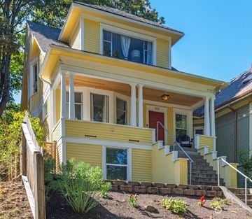 Seattle apartment for rent - A yellow house with a red door and a staircase leading to the entrance.