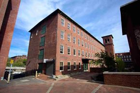 Biddeford apartment for rent - A red brick building with a green door and windows.
