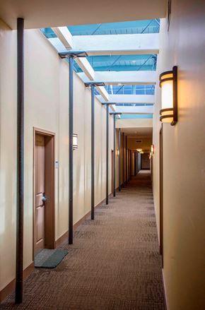 Biddeford apartment for rent - A long hallway with a carpeted floor and a skylight.