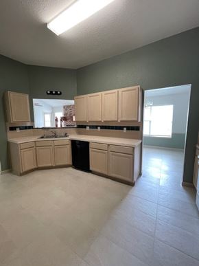 Temple house for rent - A kitchen with a black trash can and cabinets.