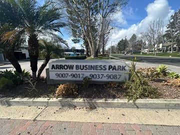 Rancho Cucamonga apartment for rent - A sign for Arrow Business Park with two phone numbers is in front of some trees.