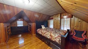 Gary house for rent - A bedroom with a bed, chair, and wooden walls.