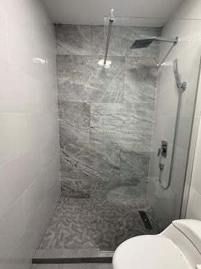 San Juan apartment for rent - A bathroom with a marble tile shower and a white toilet.