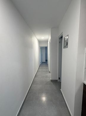San Juan apartment for rent - A long, narrow hallway with white walls and grey flooring.