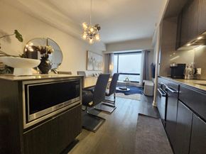 Montréal apartment for rent - A modern kitchen with a black oven and a dining area with a table and chairs.