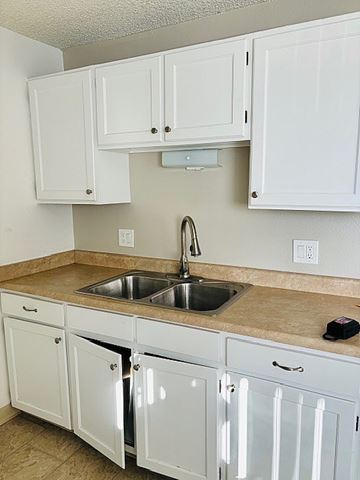 Littleton apartment for rent - A kitchen with white cabinets and a granite countertop.