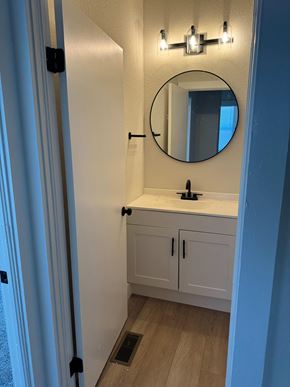 Cridersville apartment for rent - A bathroom with a round mirror and a sink.