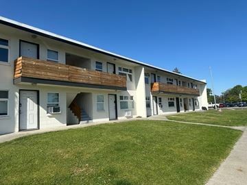 Pasco apartment for rent - A white building with a balcony and a green lawn in front.
