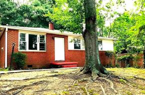Atlanta house for rent - A red brick house with a white door and windows, surrounded by trees.