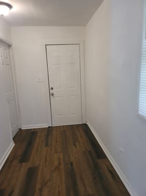 Atlanta house for rent - A white door is in the middle of a hallway with wood floors.