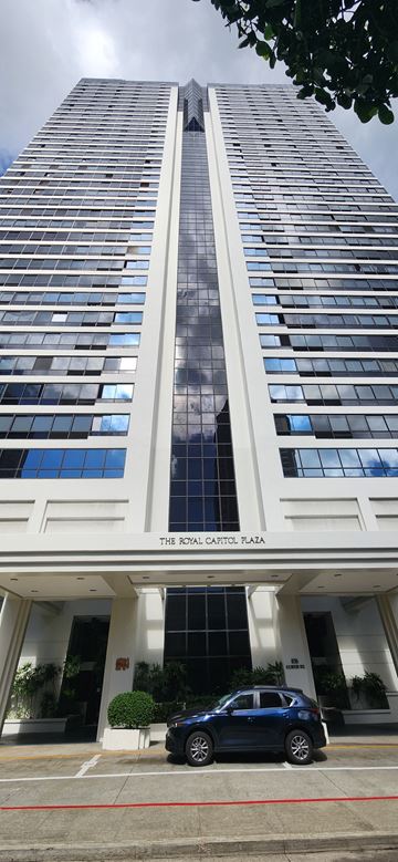 Honolulu apartment for rent - A tall white building with a black car parked in front.