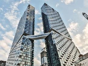 Montréal apartment for rent - Three tall buildings with glass windows and a bridge connecting them.