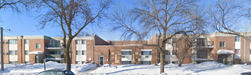 Moorhead apartment for rent - A large red brick building with a black car in front.