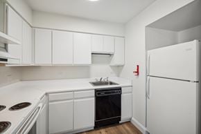 Altoona apartment for rent - A white kitchen with a black oven and a white fridge.
