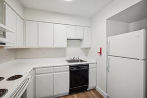 Altoona apartment for rent - A white kitchen with a black oven and a white fridge.