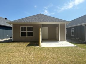 Little Rock house for rent - A small house with a grey roof and a brown door is surrounded by a grassy area.