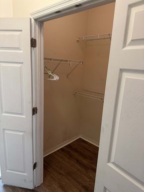 Deltona apartment for rent - A white door is open to a small closet with a shelf and clothes hangers.
