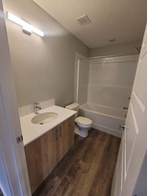 Calgary apartment for rent - A white bathroom with wood flooring and a white toilet.