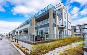 Innisfil apartment for rent - A modern building with a glass balcony and a wooden walkway in front.