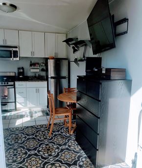 Oakland apartment for rent - A black and white patterned floor in a kitchen with a black fridge and a wooden chair.