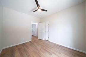 Phenix City house for rent - A room with a ceiling fan and wooden floors.