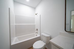 Phenix City house for rent - A white toilet in a bathroom with a white tub and sink.