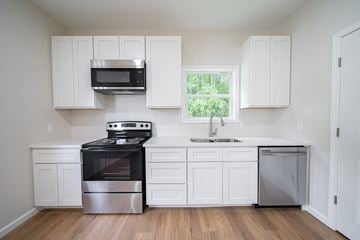 Phenix City house for rent - A kitchen with white cabinets and a window.