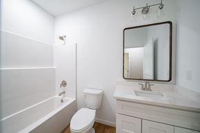 Phenix City house for rent - A white bathroom with a toilet, sink, and bathtub.