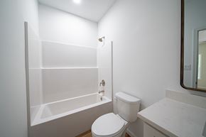 Phenix City house for rent - A white toilet in a bathroom with a white tub and sink.