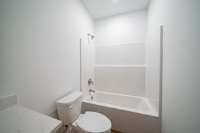 Phenix City house for rent - A white toilet sits next to a bathtub in a bathroom.