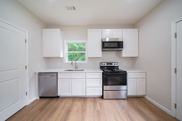 Phenix City house for rent - A kitchen with white cabinets and a window.
