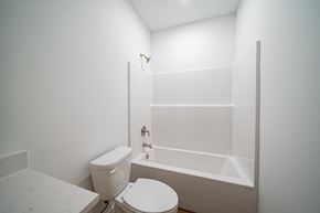 Phenix City house for rent - A white toilet sits next to a bathtub in a bathroom.