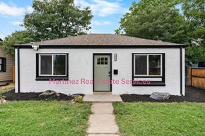 Denver house for rent - A small white house with a green door and Martinez Real Estate Services written on the front.