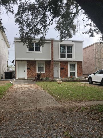 New Orleans apartment for rent - A white house with a brick facade and a white car parked in front.