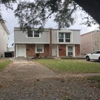 New Orleans apartment for rent - A white car is parked in front of a brick house.