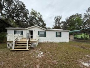 Fort Mccoy house for rent - A white house with a green awning and a wooden deck.