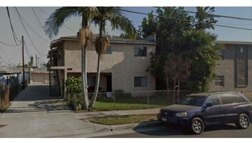 Downey apartment for rent - A grey building with a blue car parked in front.