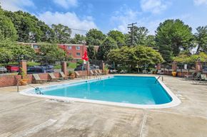 Silver Spring apartment for rent - A large outdoor swimming pool surrounded by a fence and trees.