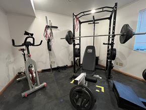 Manvel apartment for rent - A home gym with a weight bench, barbell, dumbbells, and a stationary bike.