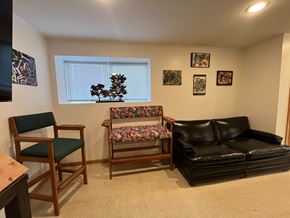 Manvel apartment for rent - A living room with a black couch, a wooden chair, and a wooden bench.