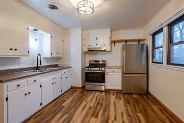 Lafayette house for rent - A kitchen with white cabinets and wooden floors.