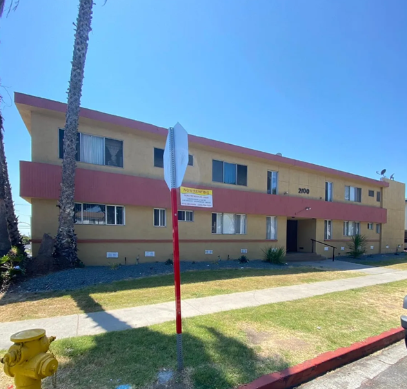 Gardena apartment for rent - A red and beige building with a white sign in front of it.