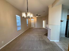 Roseville house for rent - A spacious room with a carpeted floor and a chandelier hanging from the ceiling.