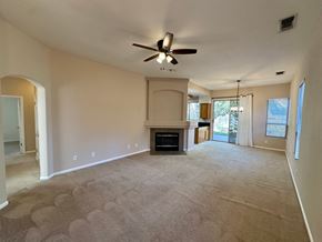 Roseville house for rent - A living room with a fireplace and a ceiling fan.